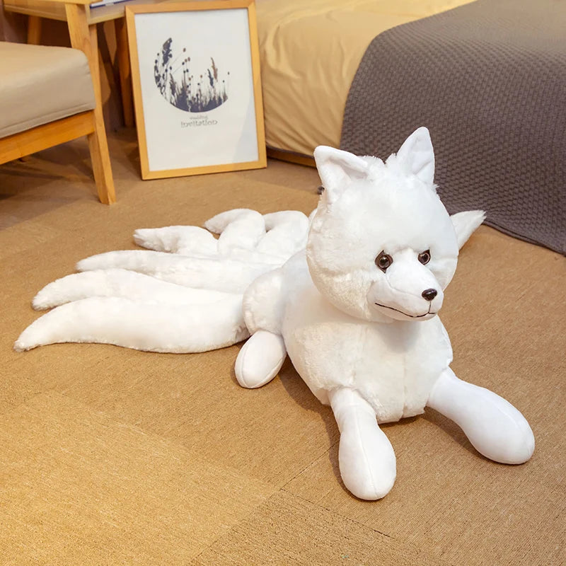 Peluche renard fantastique à neuf queues rouge et blanche couchée sur un canapé dans une chambre.