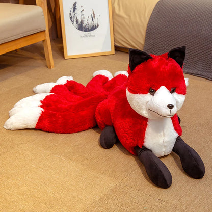 Peluche renard fantastique à neuf queues rouge et blanche couchée sur un canapé dans une chambre.