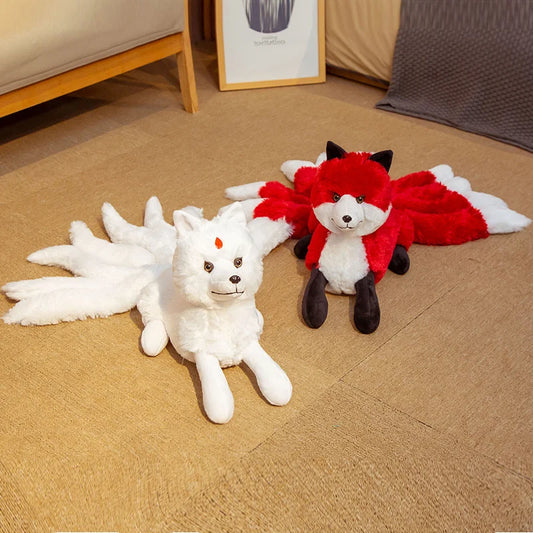 Peluche renard fantastique à neuf queues rouge et blanche couchée sur un canapé dans une chambre.
