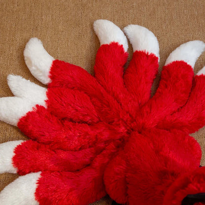 Peluche renard fantastique à neuf queues rouge et blanche couchée sur un canapé dans une chambre.